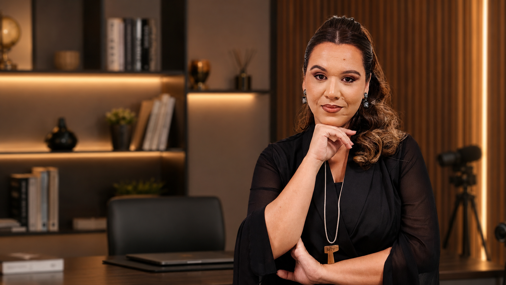 Thais Barbosa em seu escritório, apoiada na mesa, olhando para a câmera